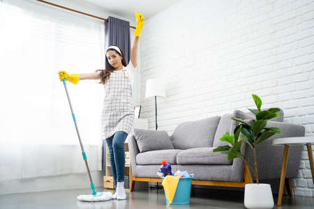 Full body portrait of a beautiful Asian woman cleaning and disinfecting all surfaces for safety...