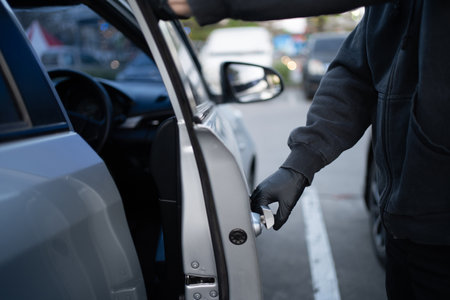 Close-up shot of a thief wearing a black shirt and black gloves. He tried to open the car door and tried to break in. car theft concept.の写真素材