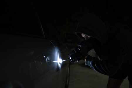 Man in black trying to steal a car. Car theft concept.