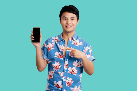 Young Asian man wearing colorful clothes at Songkran festival. He is pointing at his smartphone on a...