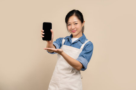 Asian female waitress portrait, isolated on light brown backgroundの写真素材