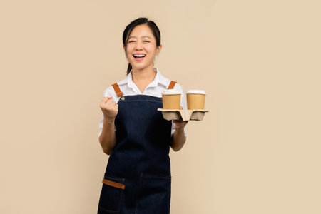 Smile Young asian waitress barista wearing apron with fists clenched celebrating victory expressing success. Startup small business.の写真素材