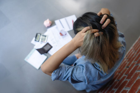 Stressed young woman calculating monthly home expenses with bank account balance and credit card bills.の写真素材