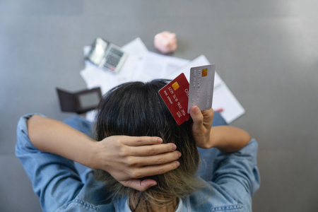 Top view of stressed young sitting Asian woman hands holding the head worry about find money to pay...