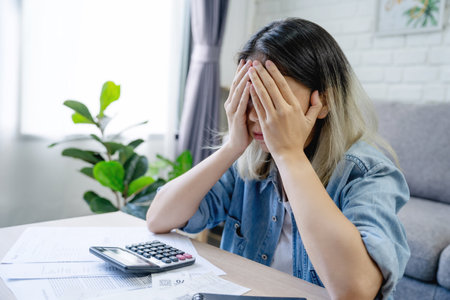 Financial owe asian woman sitting cover face with hands, stressed by calculate expense at homeの写真素材
