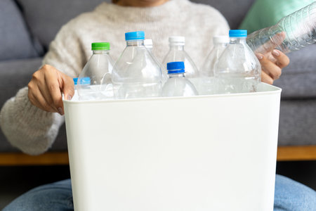 Happy Asian woman keep plastic bottle into trash bins box at home or office. Hand Sorting Recycle garbage. Environmental, trash Separation conceptの写真素材