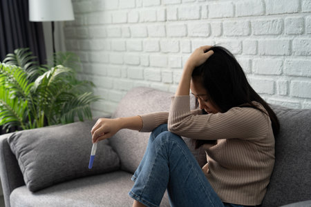 Asian woman holding pregnancy test kit, disappointed with negative result. She was unwilling to become pregnant.の写真素材