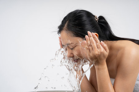 Woman washing face with clean water on white backgroundの写真素材