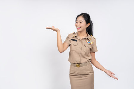 Cheerful Asian woman in Thai government uniform olding blank copy space on the palm isolated on white backgroundの写真素材