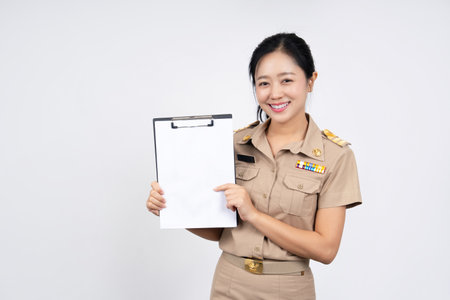 Happy Asian woman wearing brown Thai government uniform and holding document files or portfolio on hand isolated on white backgroundの写真素材