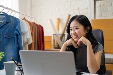 SME Startup, Small Business Entrepreneur. Smiling and relaxed Asian businesswoman  in smart casual clothing using smartphone and computer.の写真素材