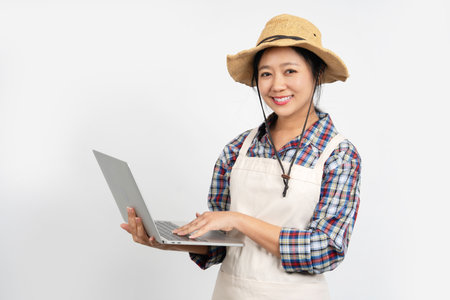 Portrait of a young Asian female farmer using a laptop against a white background.の写真素材