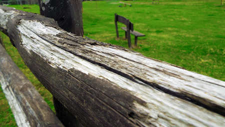 wooden fence in the foreground and in the background the bench on the lawnの写真素材