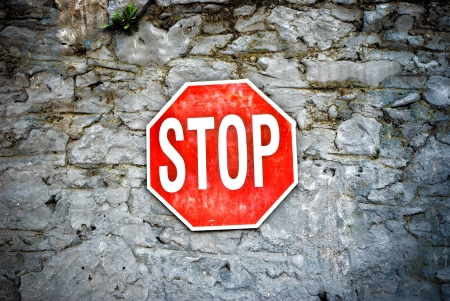 Grunge red stop sign on a stone wallの写真素材