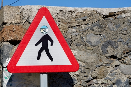close-up of a funny attention pedestrian road sign with an individual faceの写真素材