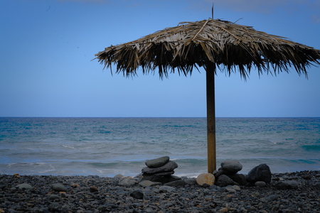 wonderfull sun umbrella at a lonely stone beachの写真素材