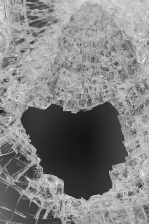 Closeup of a black hole in the center of a broken glassの写真素材