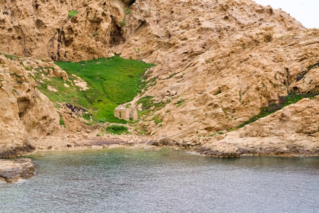background of green grass with a chuch ruin on a beige rock, the sea in the foregroundの写真素材