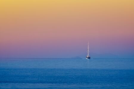 White sailing boat approching on the blue seaの写真素材
