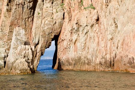 Close-up of a red-brown rock in the ocean with a mouthの写真素材