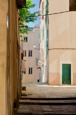Empty alleys between yellow homes with green shuttersの写真素材