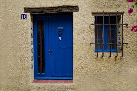 Close-up of a blue door and a blue window of a beige houseの写真素材