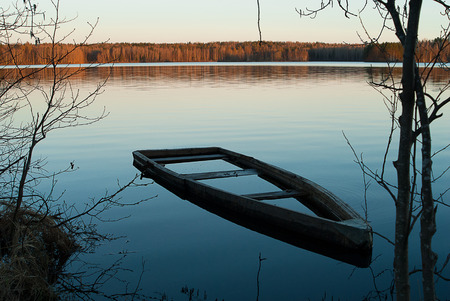 A boat flooded beside a lakeside  Somewhere in the whild Leningrad regionの写真素材