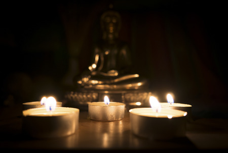 In dark of candle light with blurred Buddha statue on the background.の写真素材
