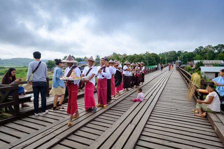Kanchanaburi, Thailand - October 14, 2016:People from the mon village crossing mon bridge. 400 m. long made by hand, wooden bridge that crosses the khao laem artificial lake, connecting the mon refugees village to sangkhlaburi village. Thailand.のeditorial素材