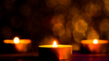 Candle flame light at night with abstract circular bokeh background Christmas lights.の写真素材