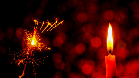 Christmas and New Year party sparkler and Candle flame light at night with abstract circular bokeh background Christmas lights.の写真素材