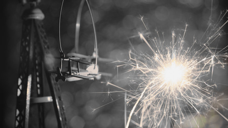 Black and white style. Toy plane with New Year party sparkler with abstract circular bokeh...