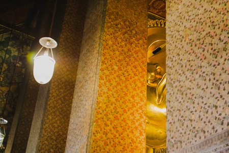 Selective face focus of Reclining golden Buddha statue with thai art architecture in church Wat Pho (Temple of the Reclining Buddha) in Bangkok,Thailand.のeditorial素材