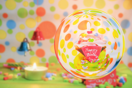 Love pink Cupcake with  inscription note - Happy Birthday and  blurred colour small bell background with glass ball effectの写真素材