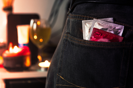 Condoms in package in jeans with blurred party background. Protection against AIDS. Safe sex concept. contraception and birth control. Protection against unwanted pregnancy.の写真素材