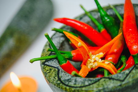 Fresh red hot chili peppers in granite mortaron and pestle  on white background.の写真素材
