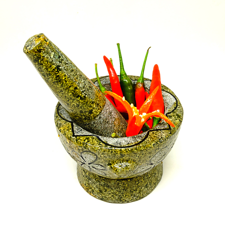 Fresh red hot chili peppers in granite mortaron and pestle  on white background.の写真素材