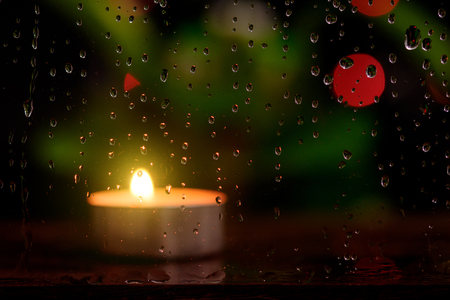 Rain drop on mirror with blurred image of candle light and bokeh light background in nightの写真素材