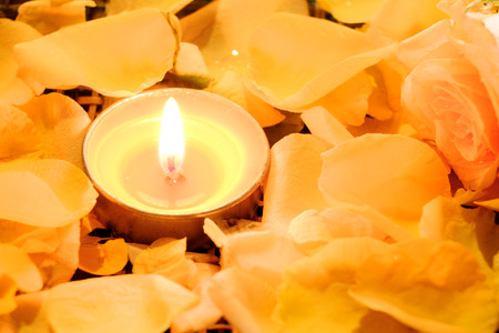 Candles light on beautiful fresh yellow rose petals with water drops on petals and dark light.の写真素材