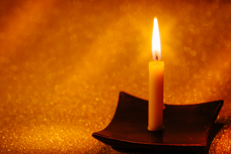 Abstract background for pray or meditation caption. Still life golden candle light with reflection on golden blurred bokeh background.の写真素材