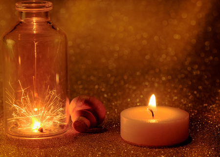 Concept of sparklers in Glass jar at night and  golden light candle burning with golden light bokeh  background.の写真素材