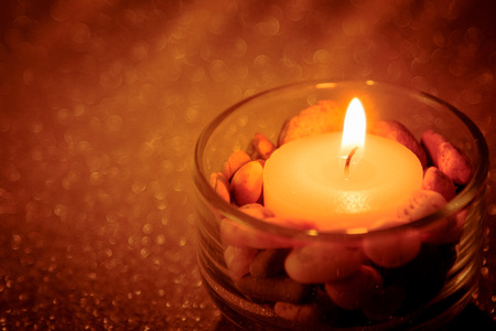 Abstract background for pray or meditation caption. Still life golden candle light with reflection on golden blurred bokeh background.の写真素材