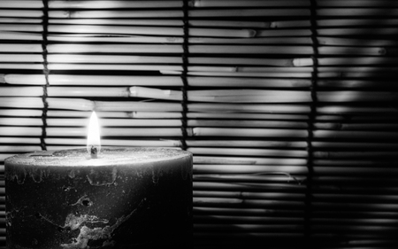 Black and white  image style.  Candle light on blurred old wooden background at the night. Selective focus on tha candle with soft  light effect.の写真素材