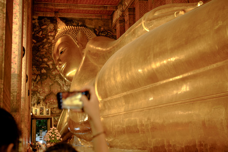The Big golden Reclining Buddha and blurred tourist taking photo by mobile, within Wat Pho temple is the landmark of Bangkok, Thailand  and Asia.のeditorial素材