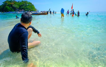 Tropical vacation holiday beach concept. Young man (tourist) relaxing on Beautiful sea blue Railay beach, Krabi Thailand .のeditorial素材