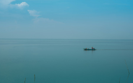 Solitary wooden fishing boat on sea with blue sky and sunylight. The concept of peace