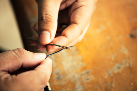 Close up shot of thread insert into a needle on human finger. concept of Success began from a small thing.の写真素材
