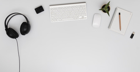 Modern office desk with keyboard, computer, notepad, headphones, 4k action camera and usb stickの写真素材