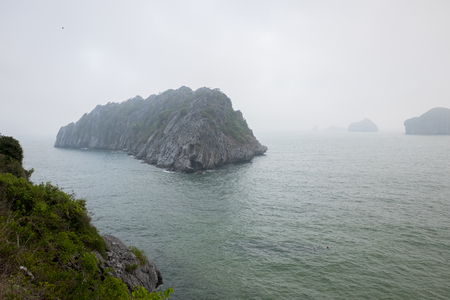Vietnam, halong, catba. Rocky island in azure sea. Blue cloudless sky. Smaller islands in backgroundの写真素材