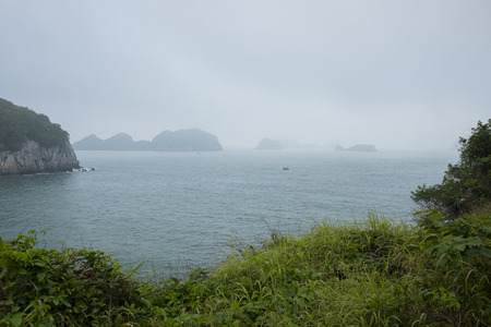 Vietnam, halong, catba. Rocky island in azure sea. Blue cloudless sky. Smaller islands in backgroundの写真素材